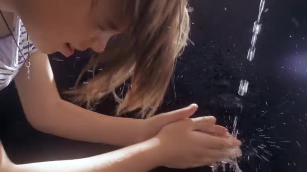 El chico caucásico se lava la cara con un chorro de agua. Fondo negro. Los soles resplandecen . — Vídeos de Stock