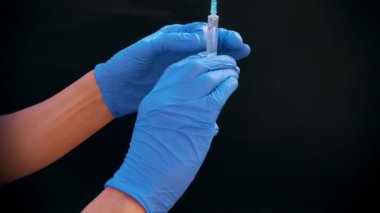 Mavi tıbbi eldivenli bir el enjeksiyon için bir şırınga tutar. Hava kabarcıklarından kurtulur. Şırıngayı ve uyuşturucu jetini kontrol ediyorum..