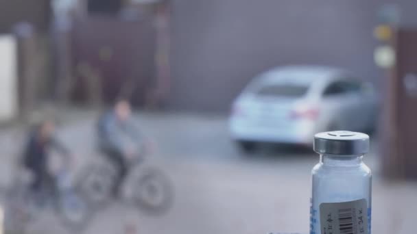 Een medicijnflesje op de voorgrond. Mensen lopen in volle concentratie door de straat. Quarantaine. — Stockvideo