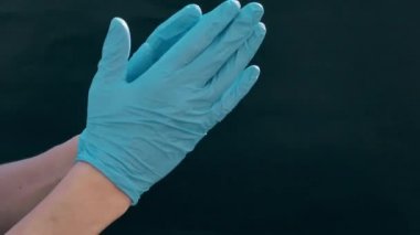 Beyaz adamların elleri mavi tıbbi eldiven giyer. Siyah arka plan. Doktoru ameliyata hazırlamak, tıbbi prosedür.