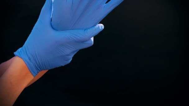 Las manos de los hombres caucásicos usan guantes médicos azules. Fondo negro. preparación del médico para la cirugía, procedimiento médico . — Vídeos de Stock
