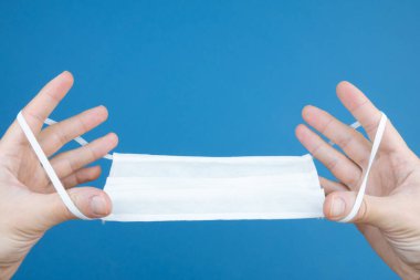 Mavi arka planda beyaz tıbbi koruyucu maske.