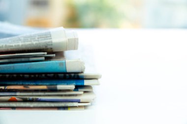 Ofisteki masada bir yığın taze sabah gazetesi var. Katlanmış ve dizilmiş günlükler