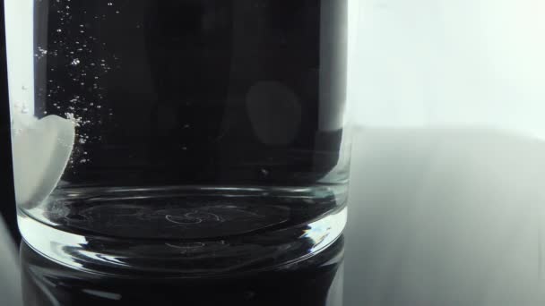 药丸的特写掉在水杯里 消泡片阿司匹林缓释在一杯水中溶解 — 图库视频影像