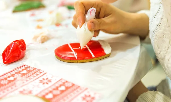 Girl painting christmas gingerbread in art studio with sweet icing