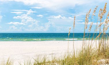 Florida 'da kumulları ve mavi gökyüzü olan güneşli St. Pete plajı.