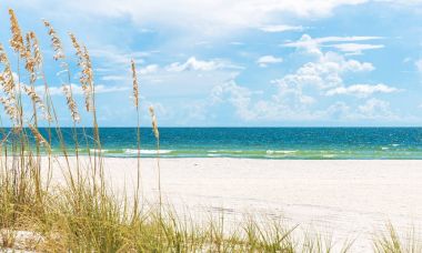 Florida 'da kumulları ve mavi gökyüzü olan güneşli St. Pete plajı.