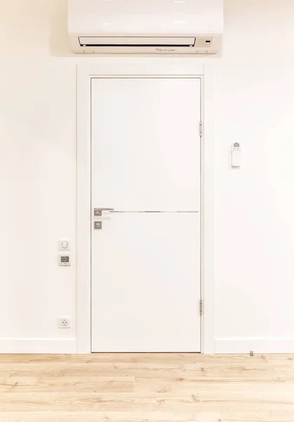 White door in modern home with air conditioner and wooden floor