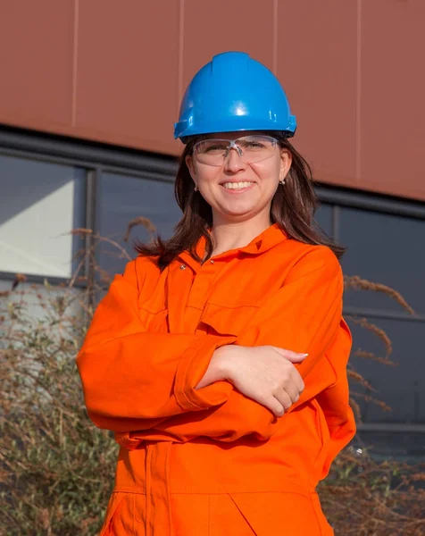 Woman worker in orange overall and blue safety helmet