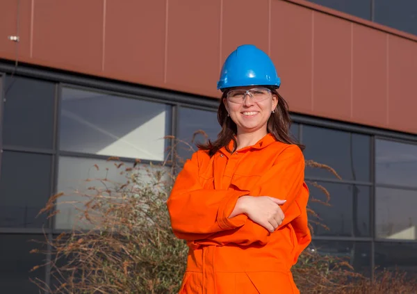 Woman worker in orange overall and blue safety helmet