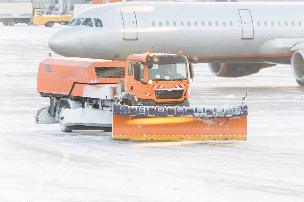 Snowplow removing snow from runways and roads in airport during 
