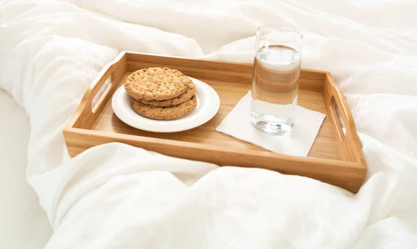 Поднос с водой и крекеры завтрак на кровати — стоковое фото