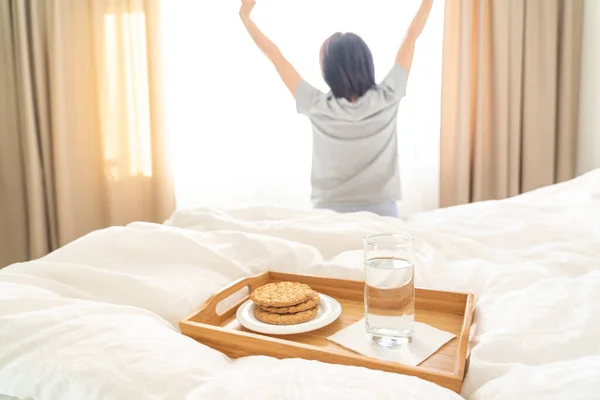 Bandeja con desayuno de dieta en una cama con la mujer estirándose en el fondo — Foto de Stock