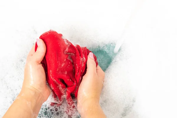 Mujer lavando ropa de color rojo con espuma detergente —  Fotos de Stock