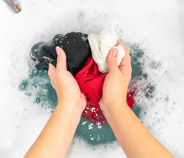 Ropa roja, negra y blanca en lavabo con espuma detergente —  Fotos de Stock