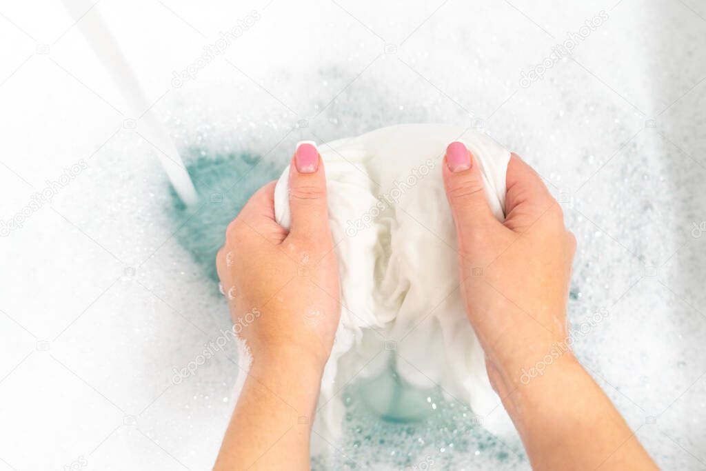 Wash clothing by hand with whitening detergent in laundry sink