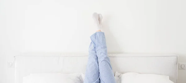 Панорама женских ног, поднятых высоко на кровати в спальне — стоковое фото