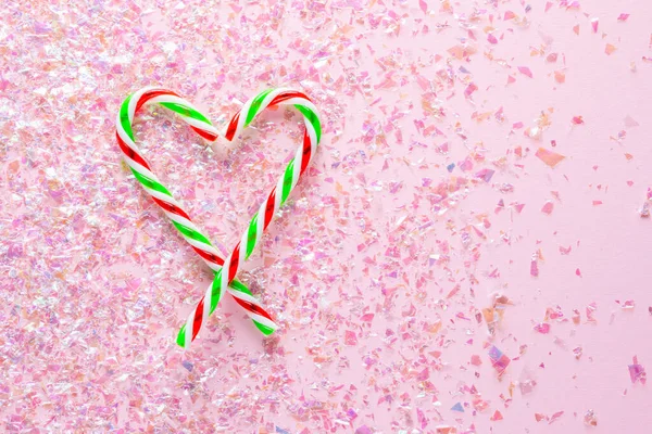 Coração feito de dois pirulitos em fundo rosa com brilho. Presentes para o Ano Novo e Natal. deitado plano — Fotografia de Stock
