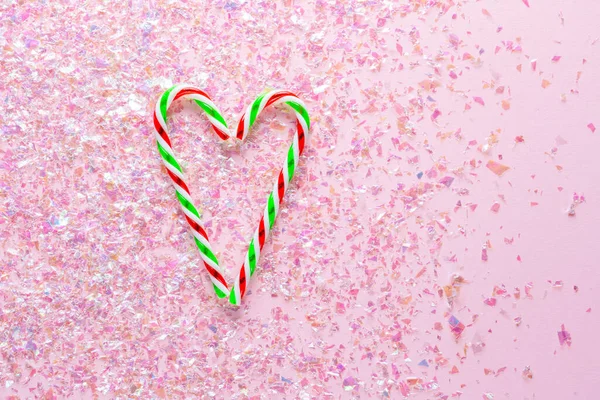 Два льодяники у формі серця на рожевому фоні з блискітками. Подарунки на Новий рік та Різдво. вид зверху — стокове фото
