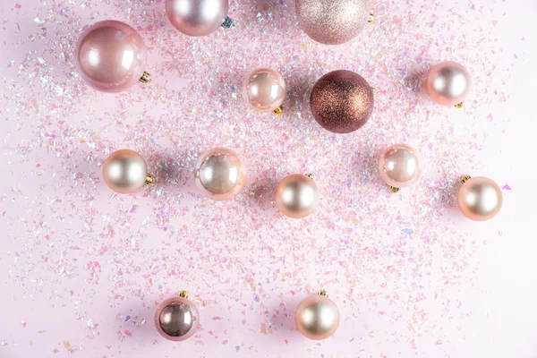 Weihnachtsdekoration aus verschiedenen eleganten Kugeln auf rosa Hintergrund mit Glitzern. flache Lage, Draufsicht — Stockfoto