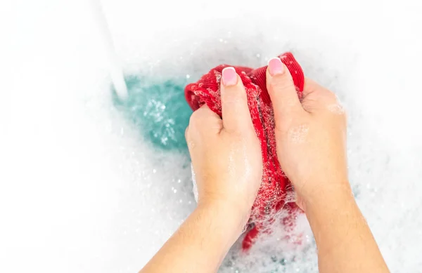 Lavado a mano de ropa roja en el fregadero con espuma con espacio para copiar —  Fotos de Stock
