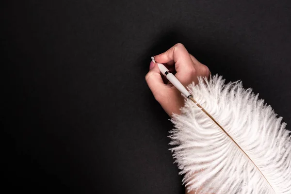 Pluma de mano femenina con pluma sobre superficie negra —  Fotos de Stock