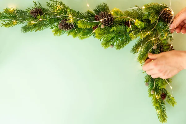 Mulher fazendo árvore de Natal com decoração de canto no fundo verde, flat lay — Fotografia de Stock