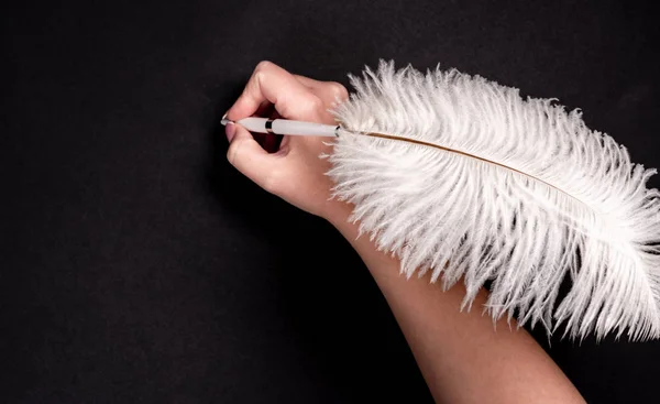 Pluma de mano femenina con pluma sobre superficie negra —  Fotos de Stock