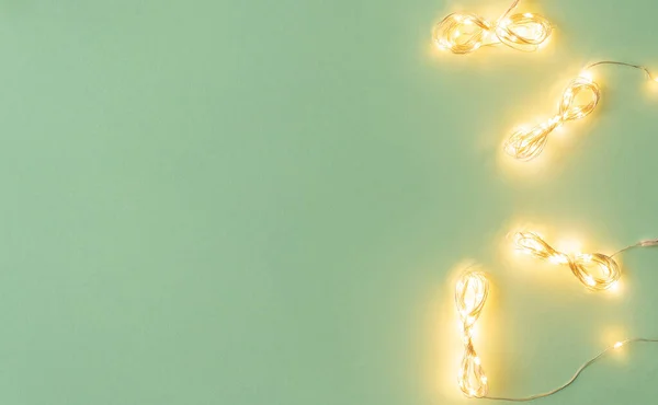 Luzes de Natal no fundo verde claro, flat lay com guirlanda de férias — Fotografia de Stock