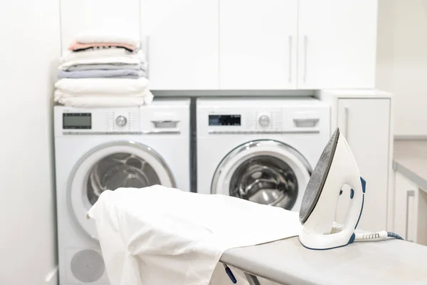 Żelazko na desce do prasowania z białą koszulą w pralni — Zdjęcie stockowe