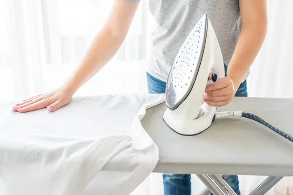 Manos femeninas planchando camisa blanca en tabla de planchar — Foto de Stock