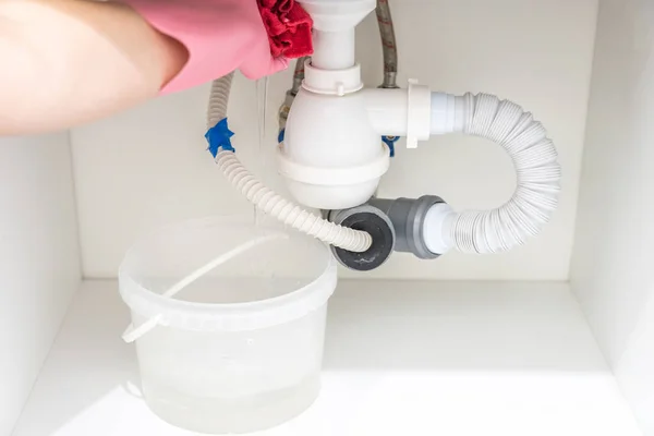 Утечка воды из пластиковой трубы под раковиной в прачечной — стоковое фото