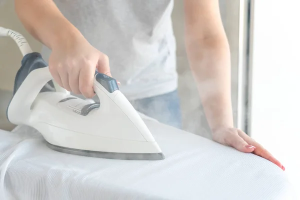 Female hands ironing white shirt on ironing board — Stock Photo, Image