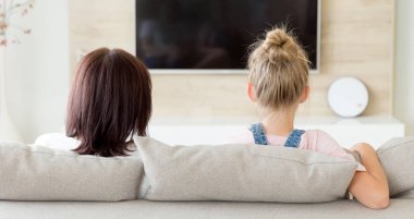Anne ve kız kanepede oturup televizyon izliyorlar. Aile zamanı konsepti, arka plan.