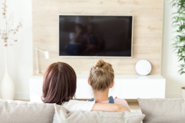 Anne ve kız kanepede oturup televizyon izliyorlar. Bekar anne kavramı, arka plan.