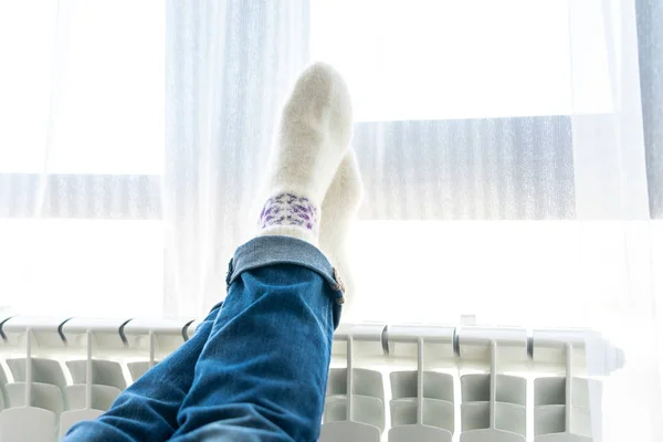 Kadın yün çorap giyiyor, ayakları ısıtıcıda. — Stok fotoğraf