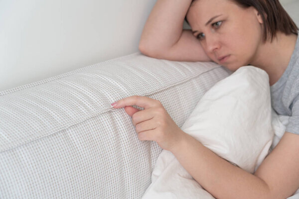 sad woman sitting on the bed holding pillow