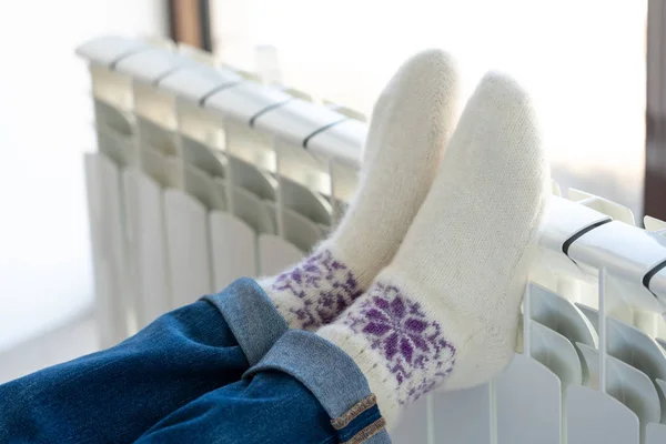 Isıtıcıda ayaklarıyla ısınan kadın yün çorap giyiyor. — Stok fotoğraf
