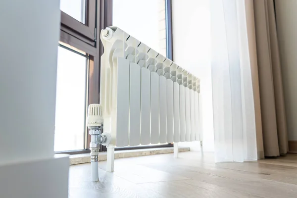 Grand radiateur blanc avec thermostat près de la fenêtre dans une pièce moderne — Photo