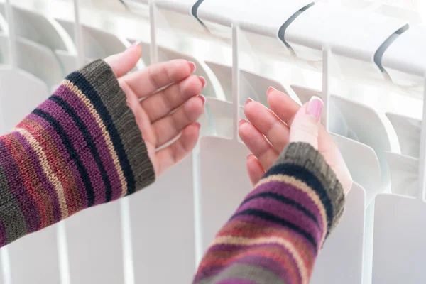 Mädchen wärmt gefrorene Hände über heißem Heizkörper, Nahsicht — Stockfoto