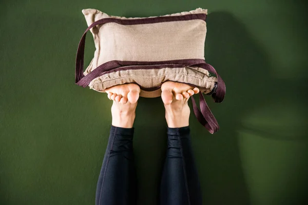 Yoga yapan genç bir kadın bacaklarını duvara dayamış, kum torbalarıyla dinleniyor. — Stok fotoğraf