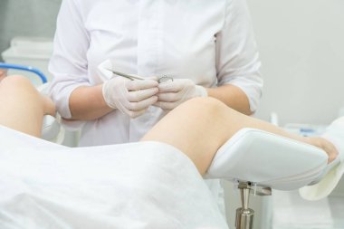 Profesyonel jinekolog kadın hastayı jinekoloji kürsüsünde muayene ediyor.