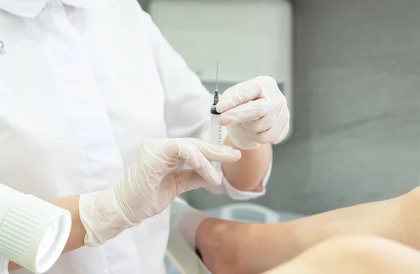 Gynekolog drží injekční stříkačku připravenou k injekci pacientovi v gynekologickém křesle — Stock fotografie
