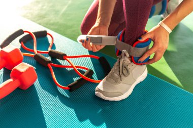 Spor salonunda egzersiz yapmadan önce bileklik takan kadın, halterli sağlık ve spor konsepti.