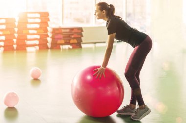 Spor salonundaki kadın pilates topuyla egzersiz yapıyor.
