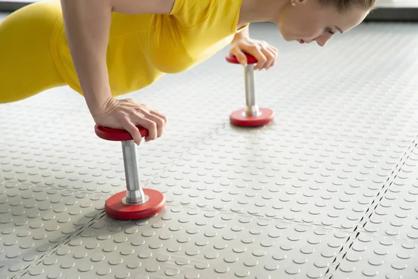 Kvinnliga händer håller hantel motion vikter stående på golvet i gym — Stockfoto
