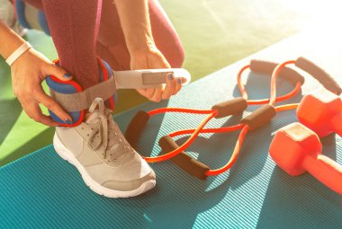 Spor salonunda egzersiz yapmadan önce bileklik takan kadın, halterli sağlık ve spor konsepti.