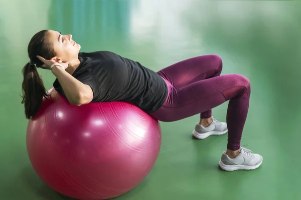 Γυναίκα στο γυμναστήριο κάνει ασκήσεις με μπάλα πιλάτες στην πλάτη της — Φωτογραφία Αρχείου