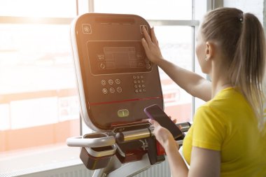 Spor salonundaki eğitim makinesinin ayarlarını ayarlayan kadın