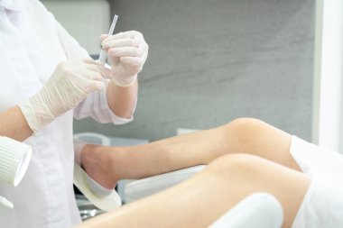 Şırıngalı jinekolog, jinekoloji koltuğundaki hastaya iğne yapıyor.